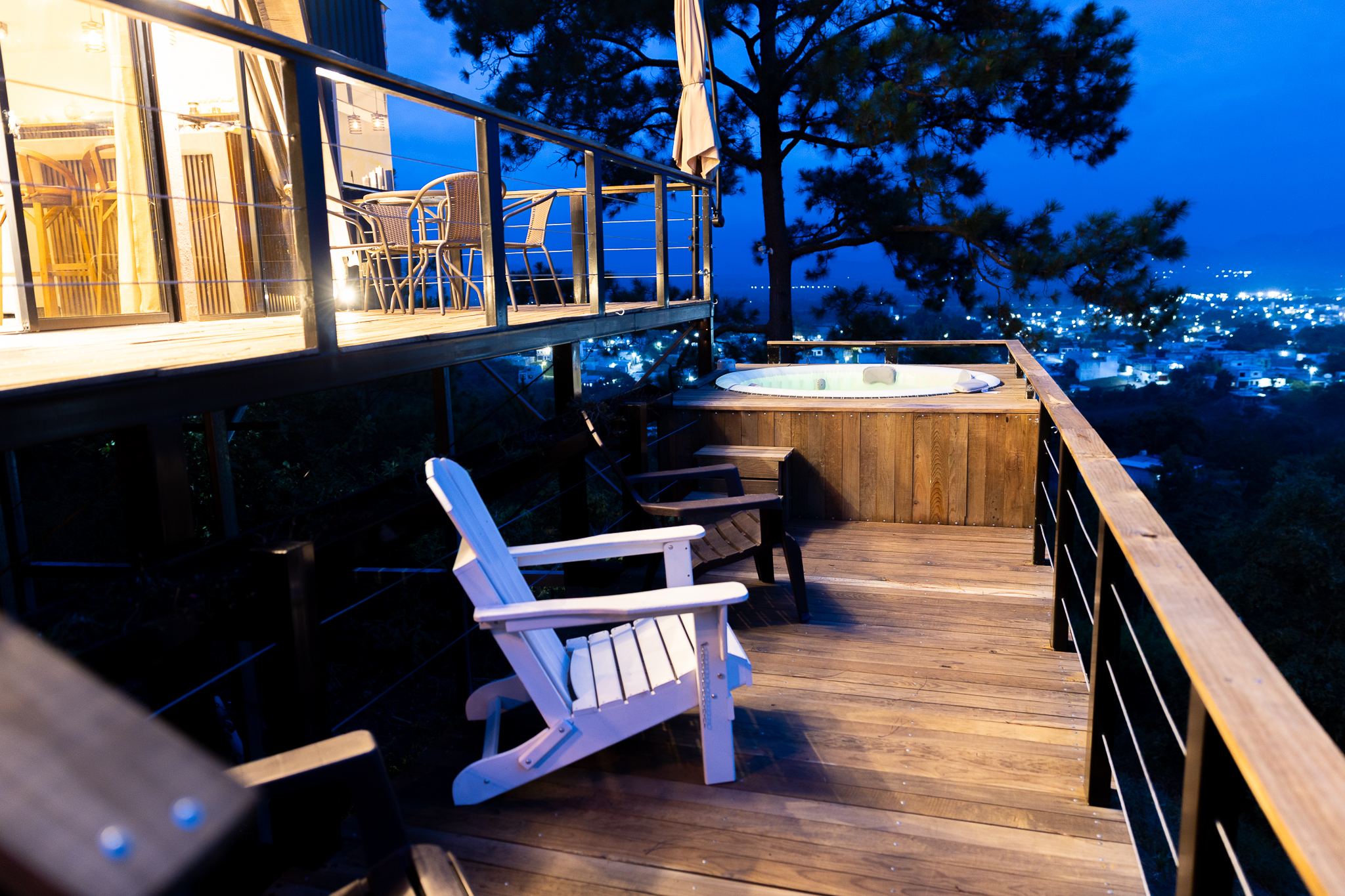 Silla Adirondack en el deck inferior junto al jacuzzi y la ciudad iluminada